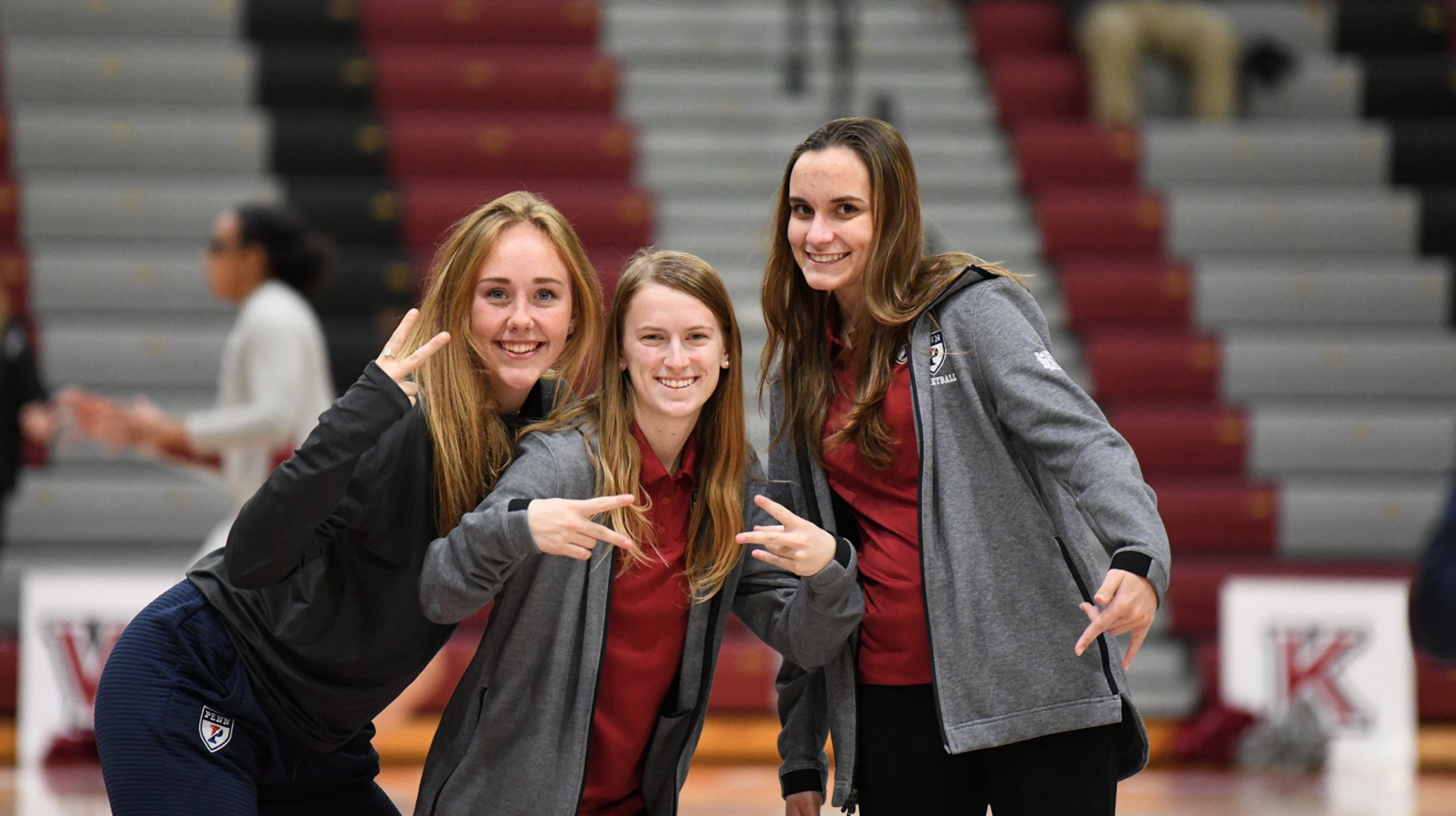 Liz Satter, left, throws up the piece sign while posing with the two women's basketball team managers.