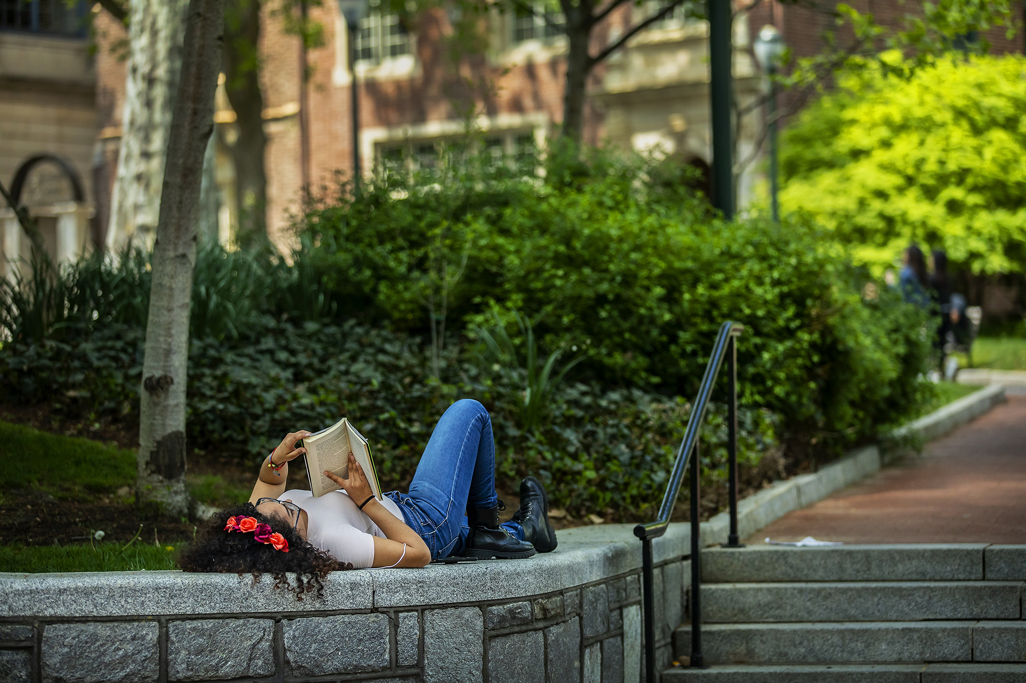 Person lies down reading on campus