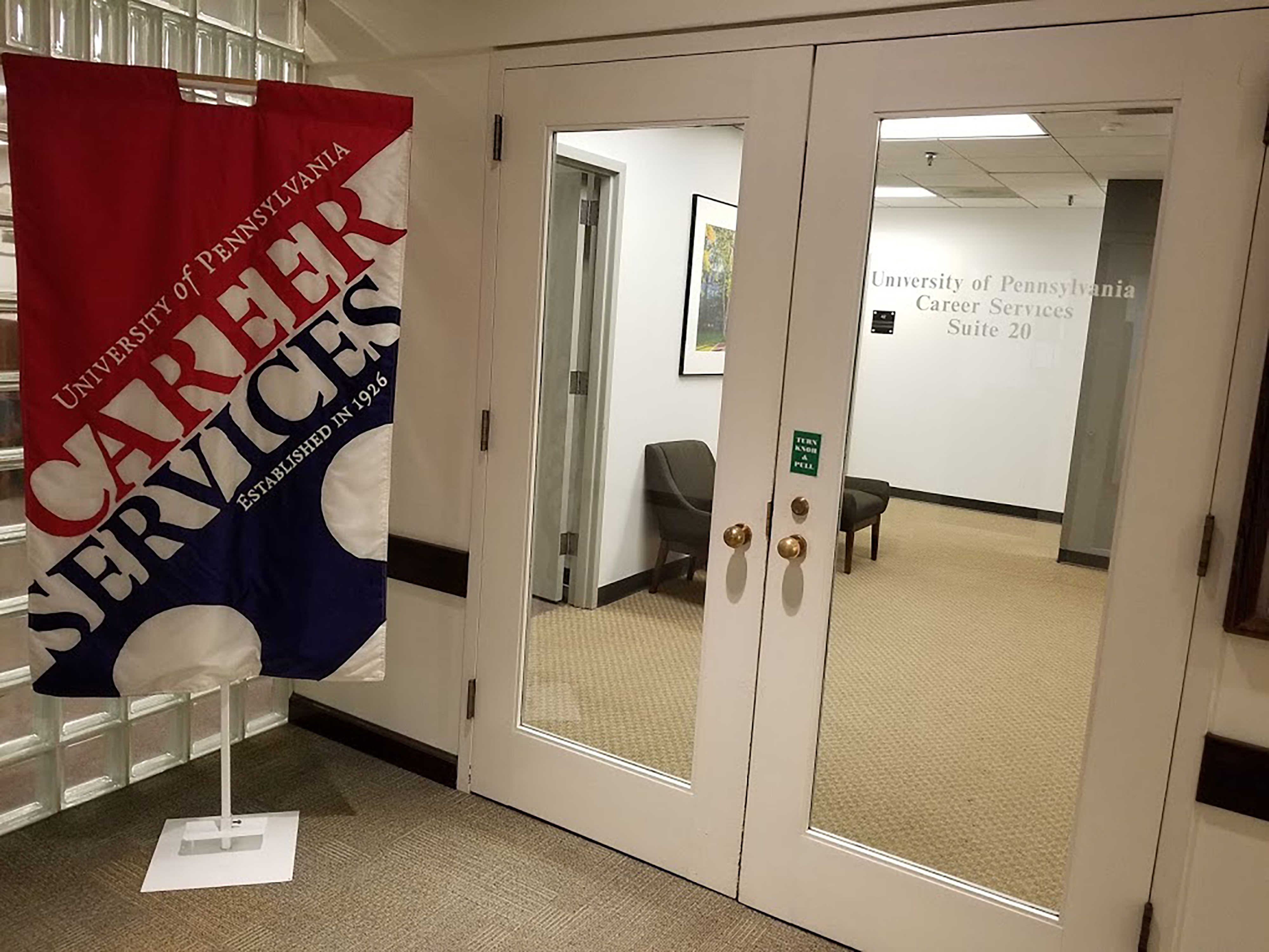Double doors lead into a waiting area. A large banner to the left reads, "University of Pennsylvania Career Services Established in 1926. 