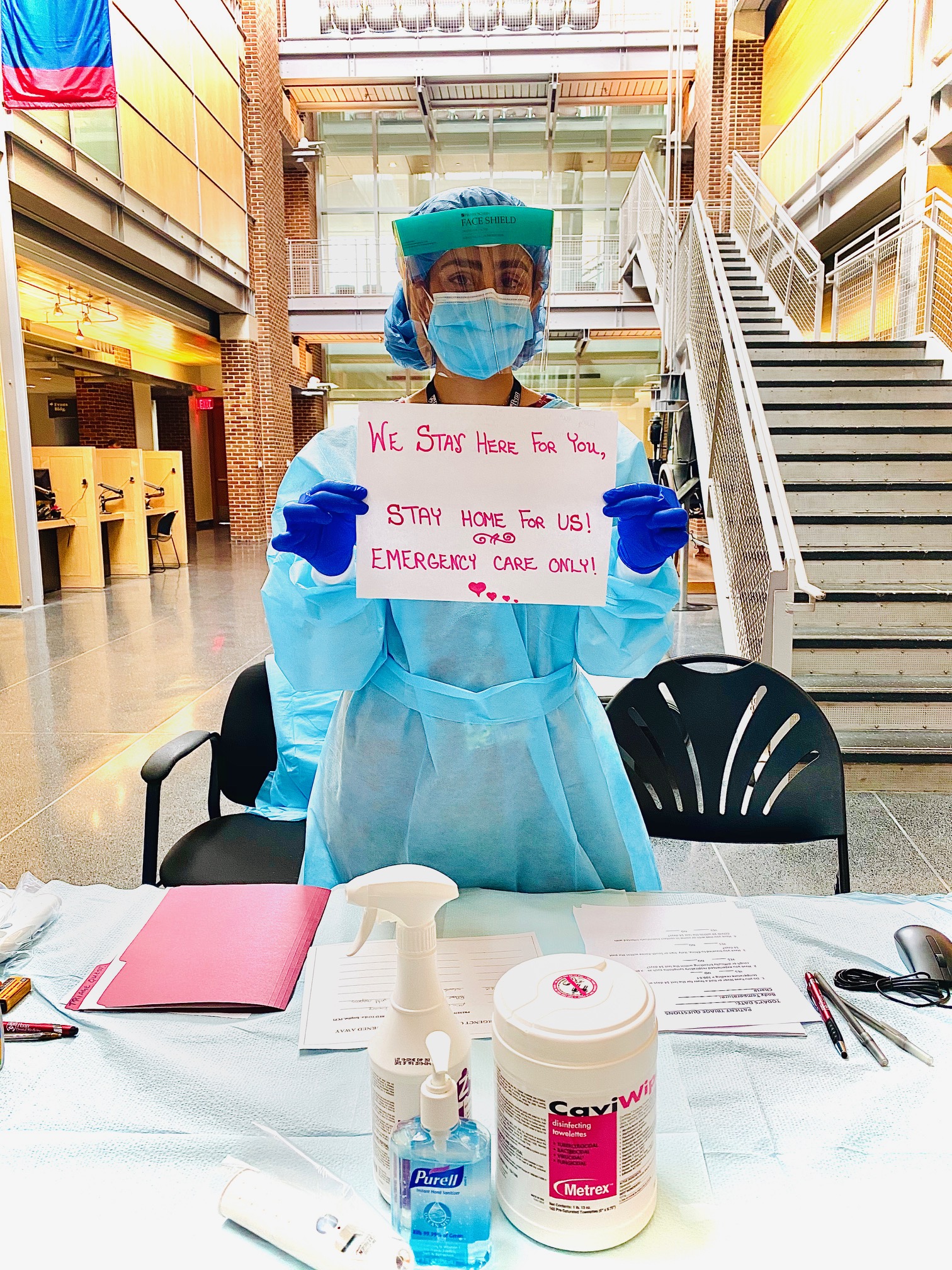 Dental worker with sign that reads We stay here for you stay home for us emergency care only
