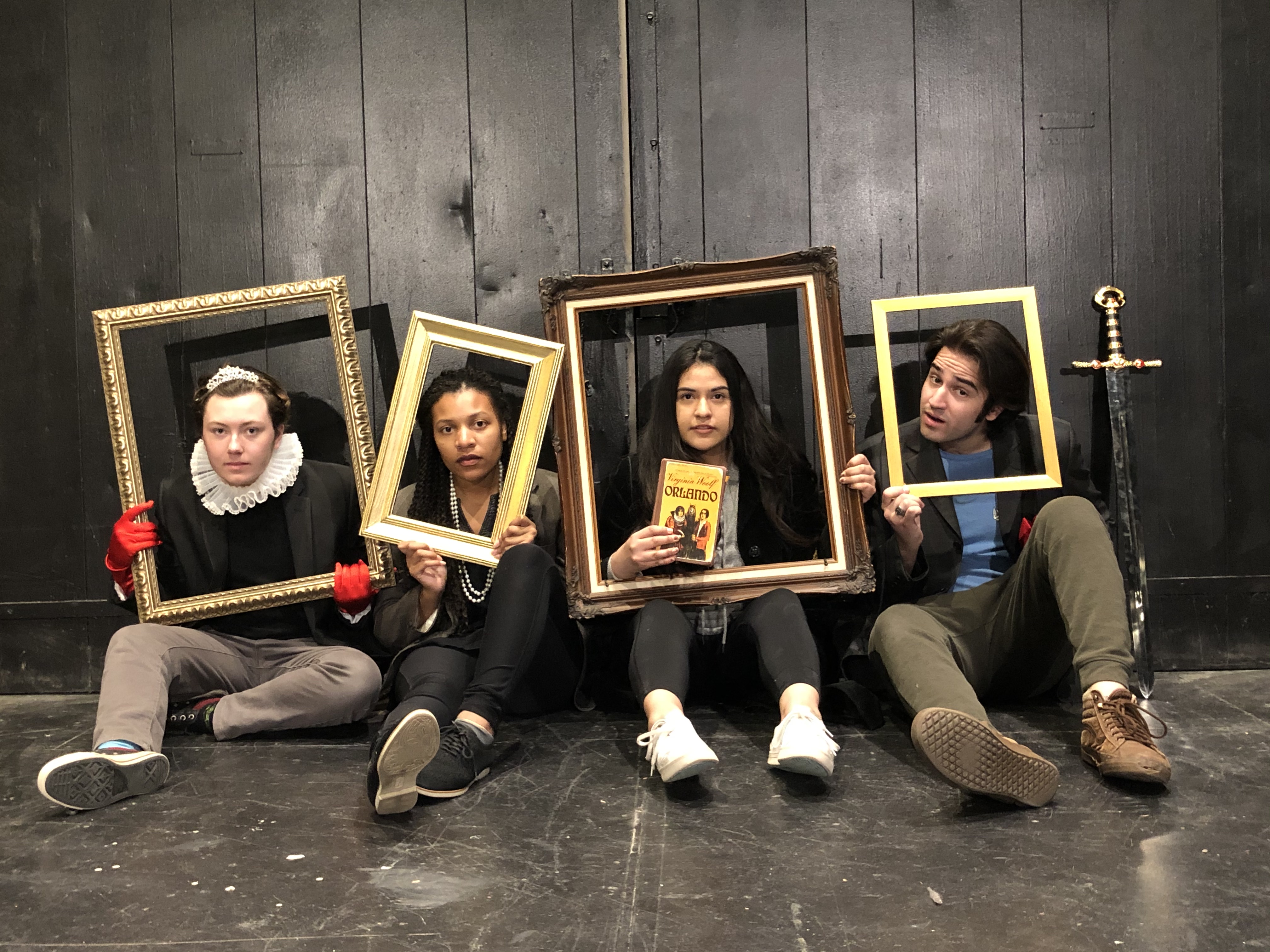 Four students sitting on the floor each with a frame around their faces, one of them holding the book titled Orlando.