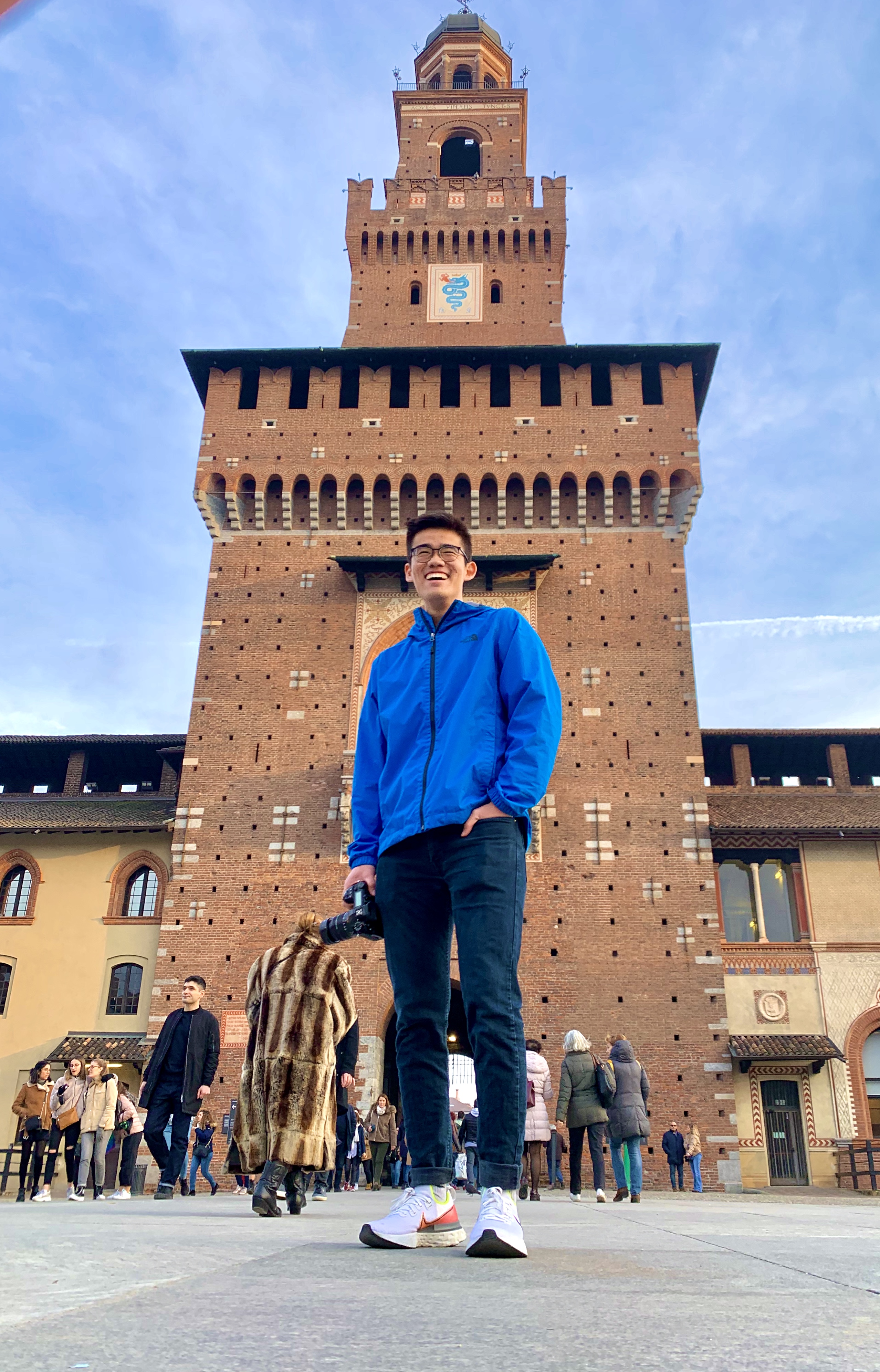 Smiling man in glasses poses in front of a tower