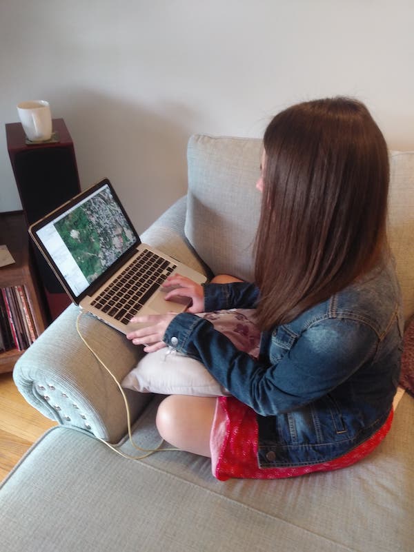 Side view of person sitting on a couch crossed-legged using a laptop.