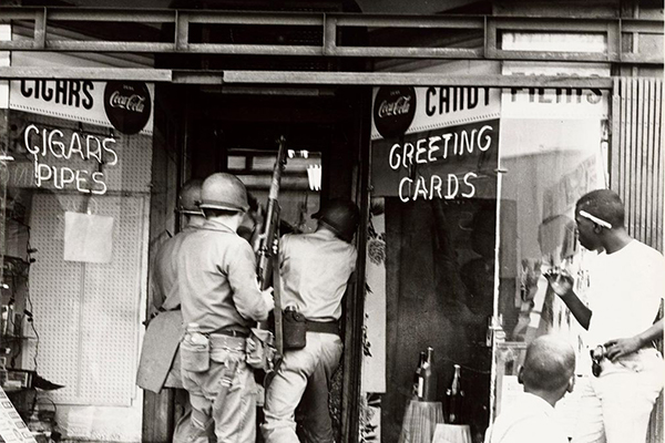 Historic image of police storming a storefront in 1967 during a riot in Detroit.