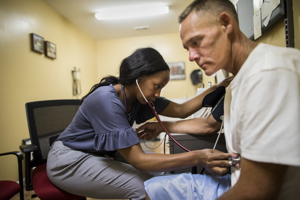 health care worker listens to the heartbeat of a patient with a stethoscope.