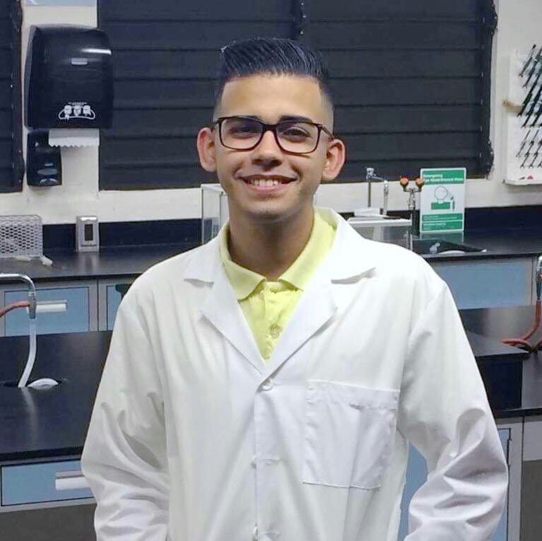 Pedro Medina, a student from the University of Puerto Rico, in a lab coat in a lab