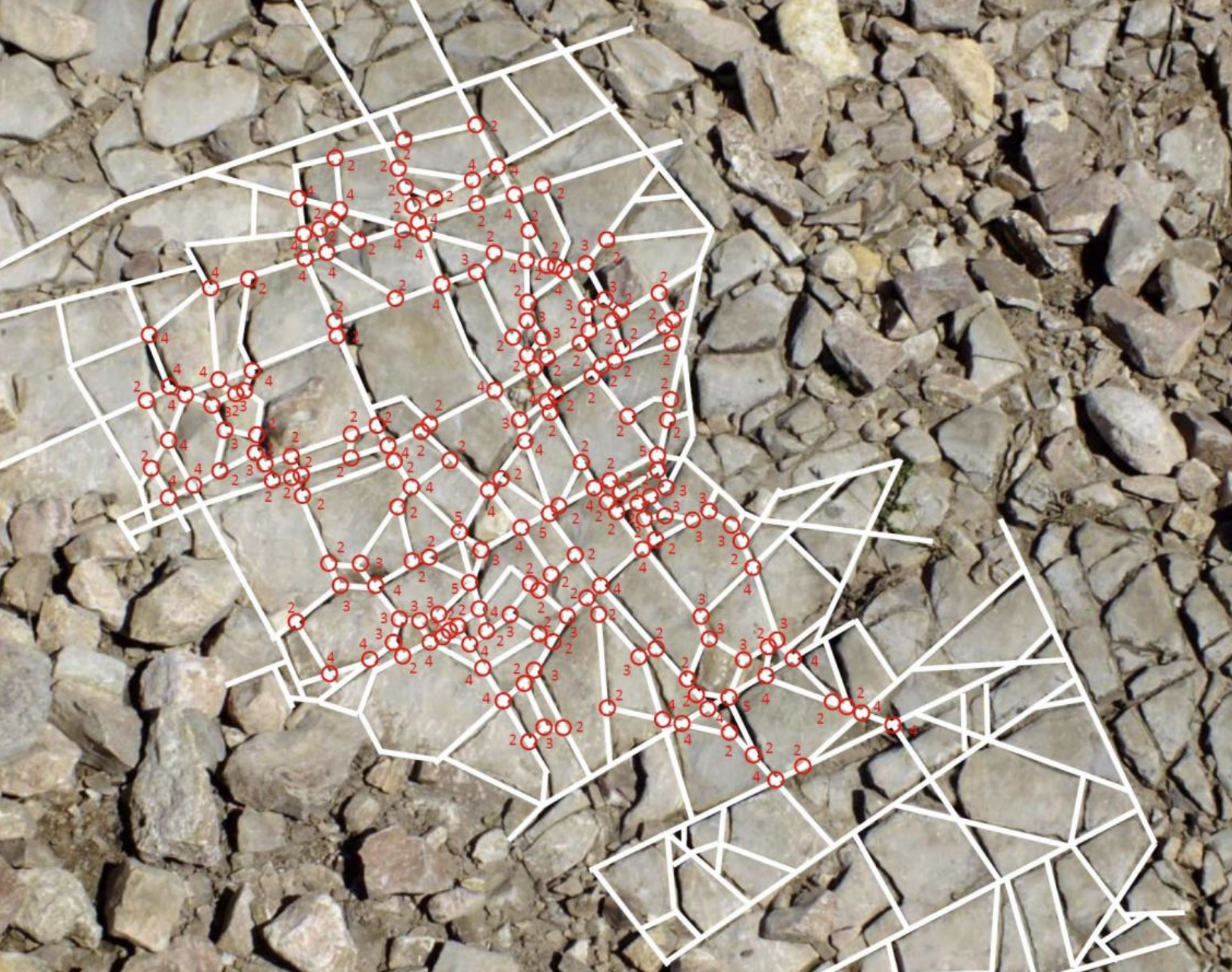 Photo of rocks overlaid with white lines and red circles indicating their sides and vertices