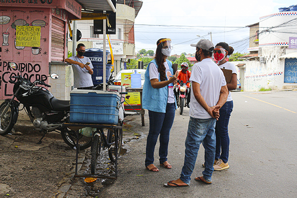 People wearing face masks chat on the street in Olinda, Brazil