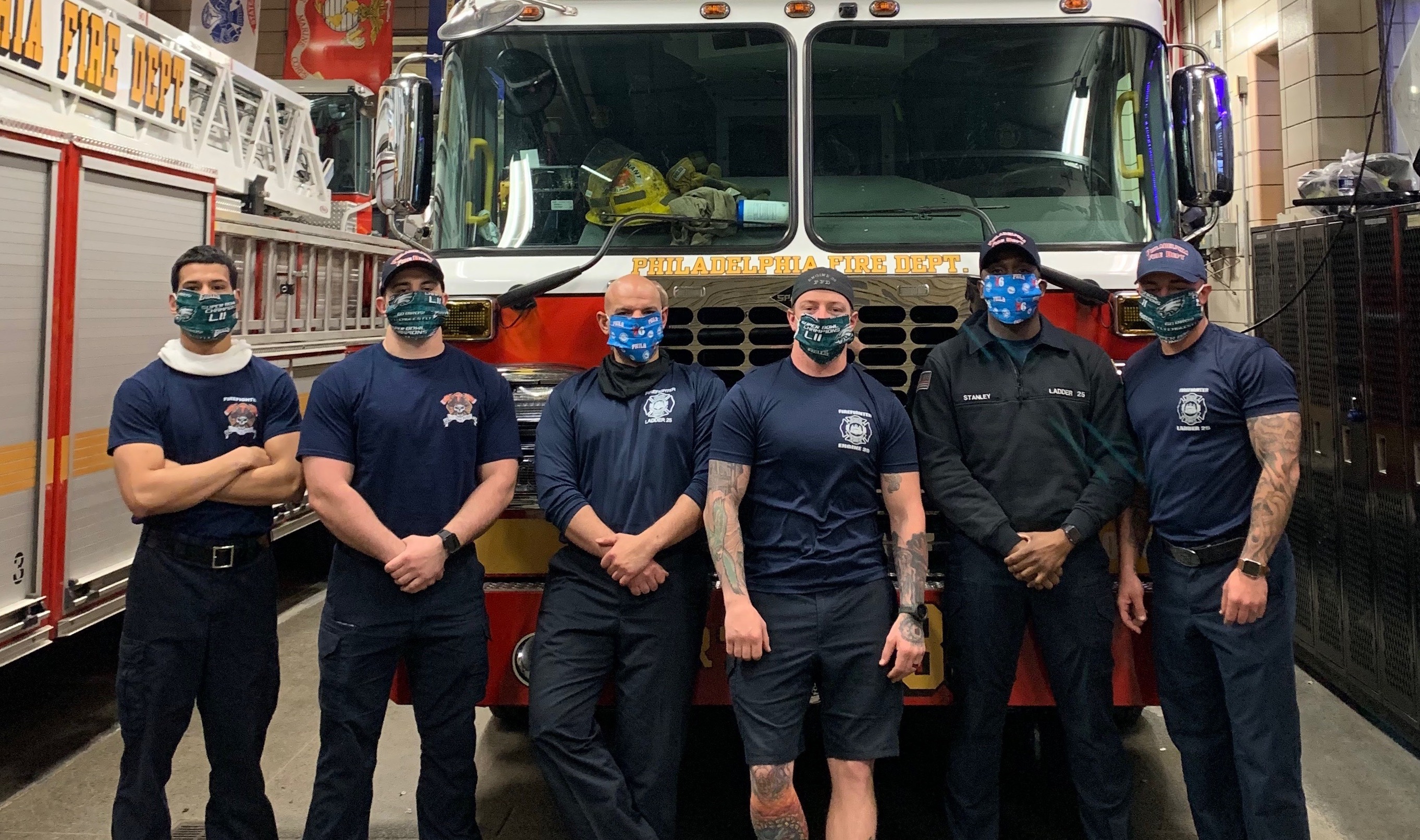 Fire fighters wearing masks stand in front of a fire truck