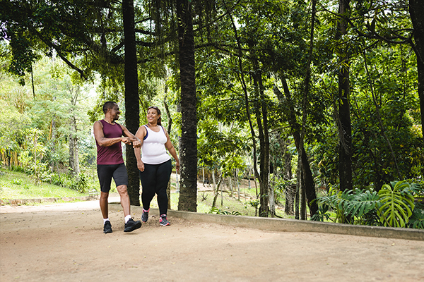 Two people in athletic gear walking on tree-lined path