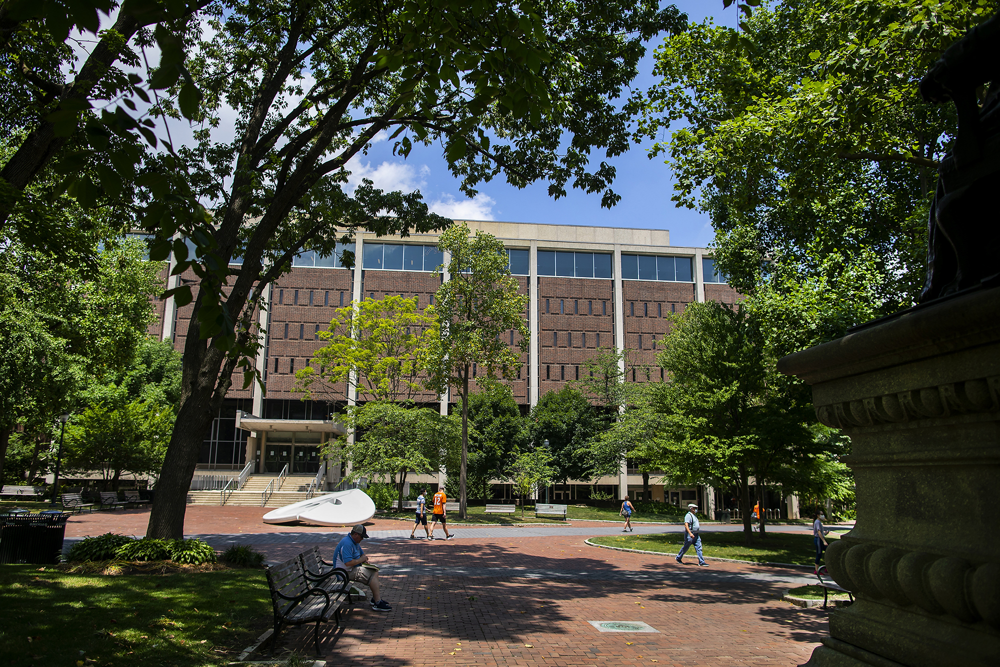 Outside picture of Penn campus with people walking and sitting on a bench