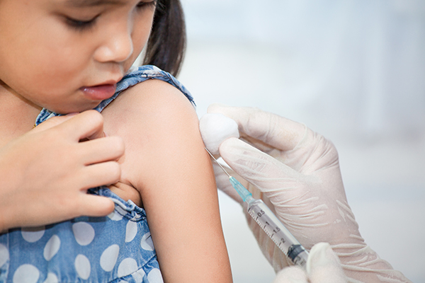 small child receiving a vaccine shot in the upper arm.