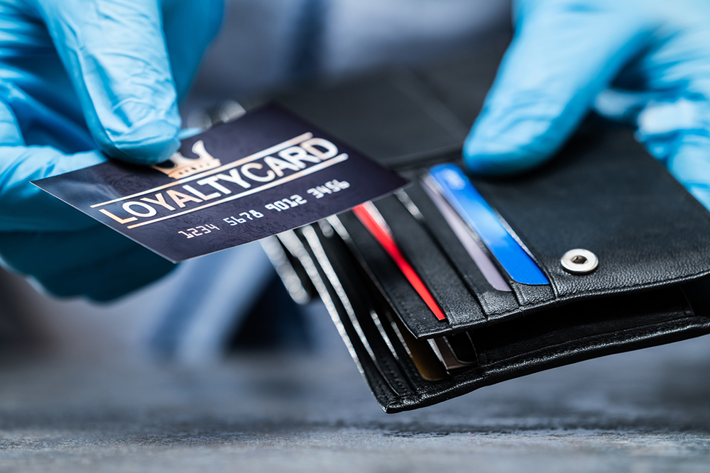 picture of open wallet with person wearing gloves holding a card with the words "loyalty card" on it