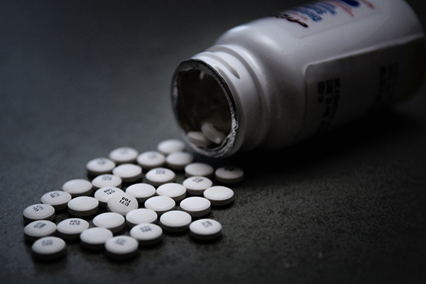 Overturned bottle of prescription pills on a surface.
