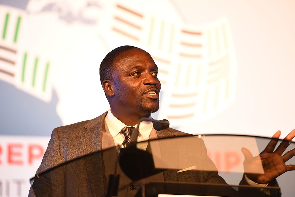 Akon speaking at a podium.