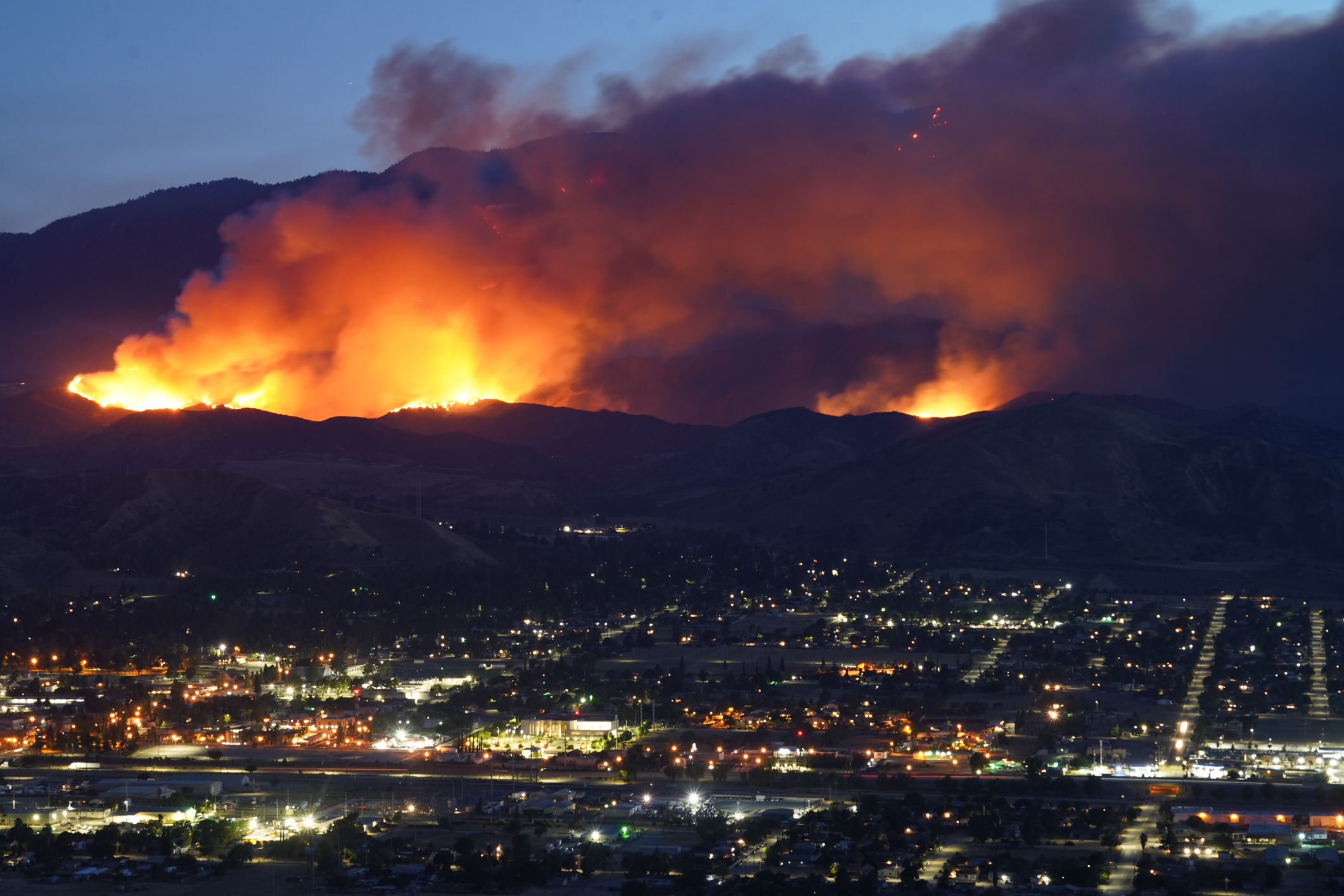 A large wildfire burns in the mountains above a California city.