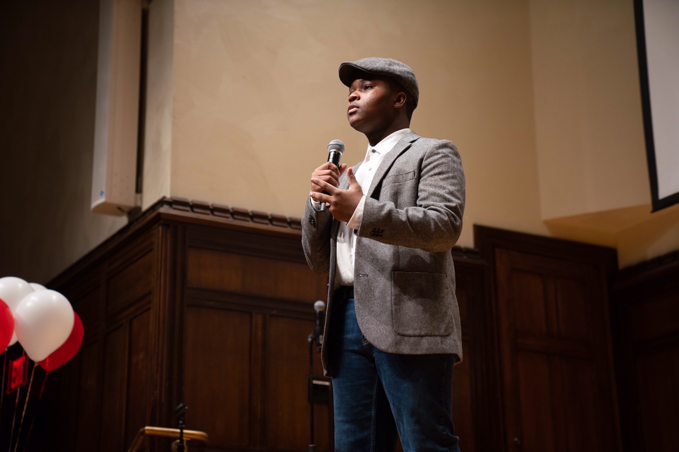 Student standing on stage speaking into a microphone