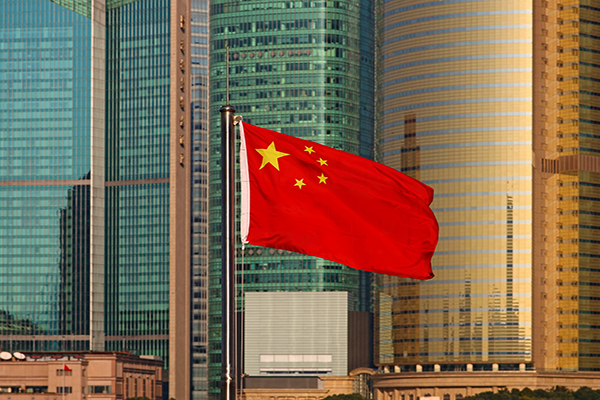 Chinese flag flies in front of modern skyscrapers