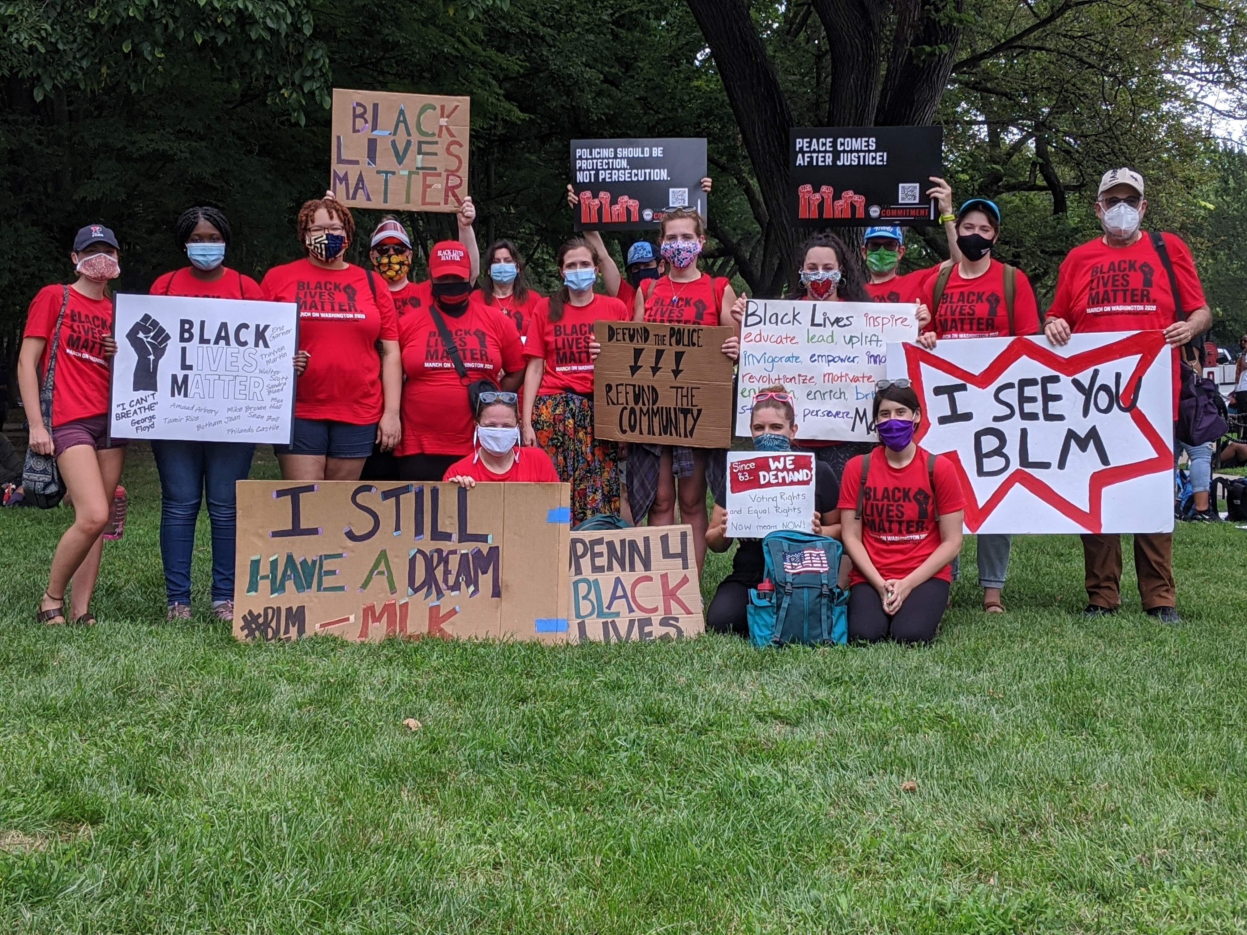Students, faculty, and staff pose with Black Lives Matter signs while sitting and standing in the grass in Washington, D.C.
