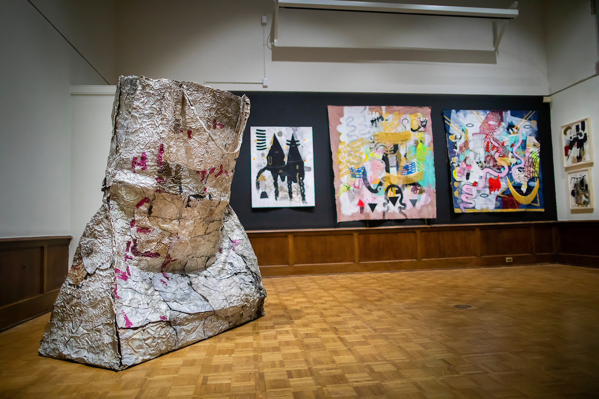 A large bag on the floor and five artworks on the wall.