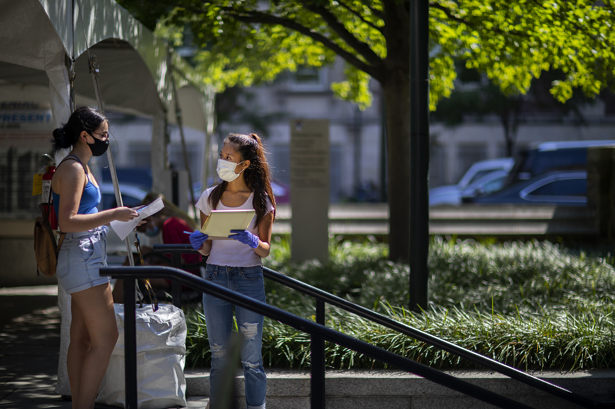 two people wearing masks talking in front of a tent entrance to a covid testing site