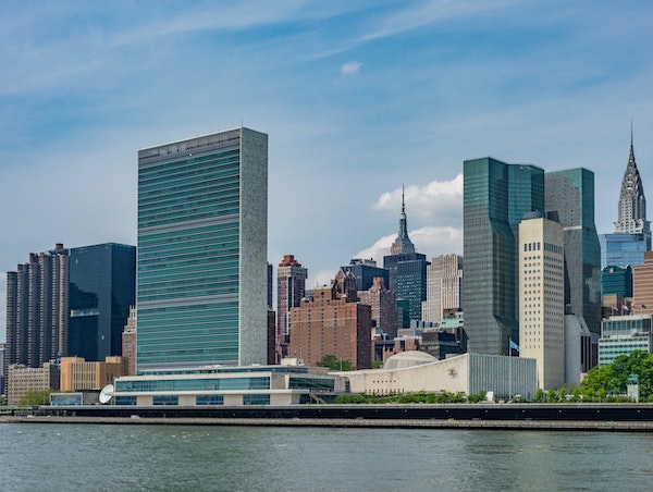 A view of the United Nations along the East River, with the Empire State Building and the Chrysler Building in the background.