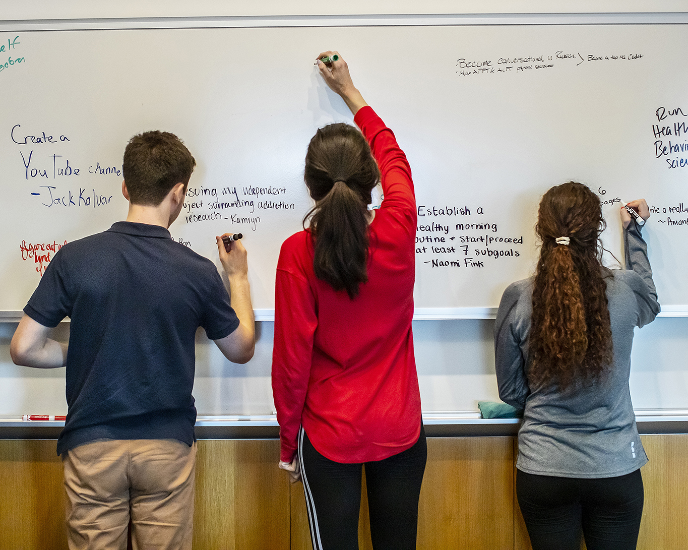three students at a white board