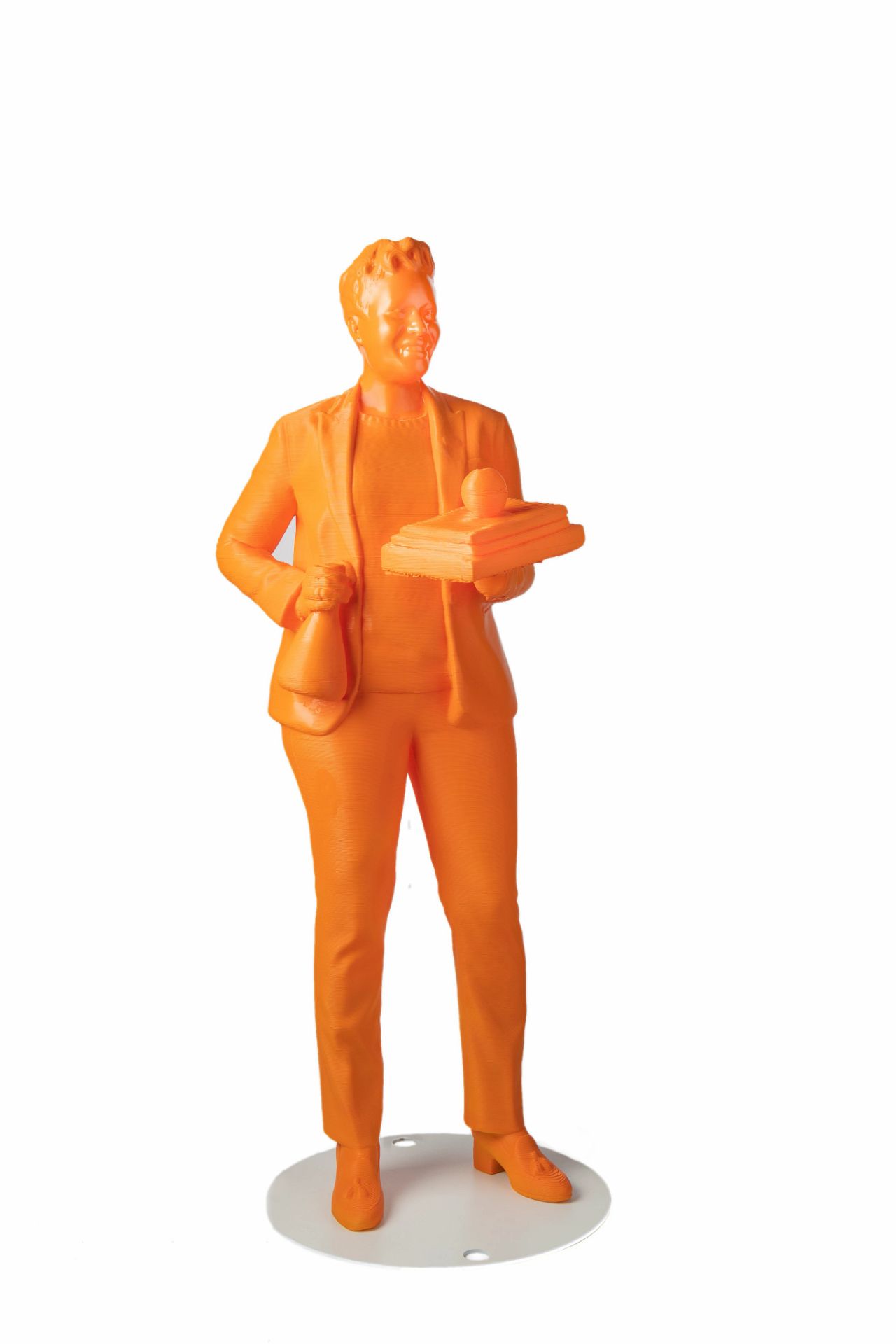 Orange model of a person standing, holding a piles of books with an apple on top.