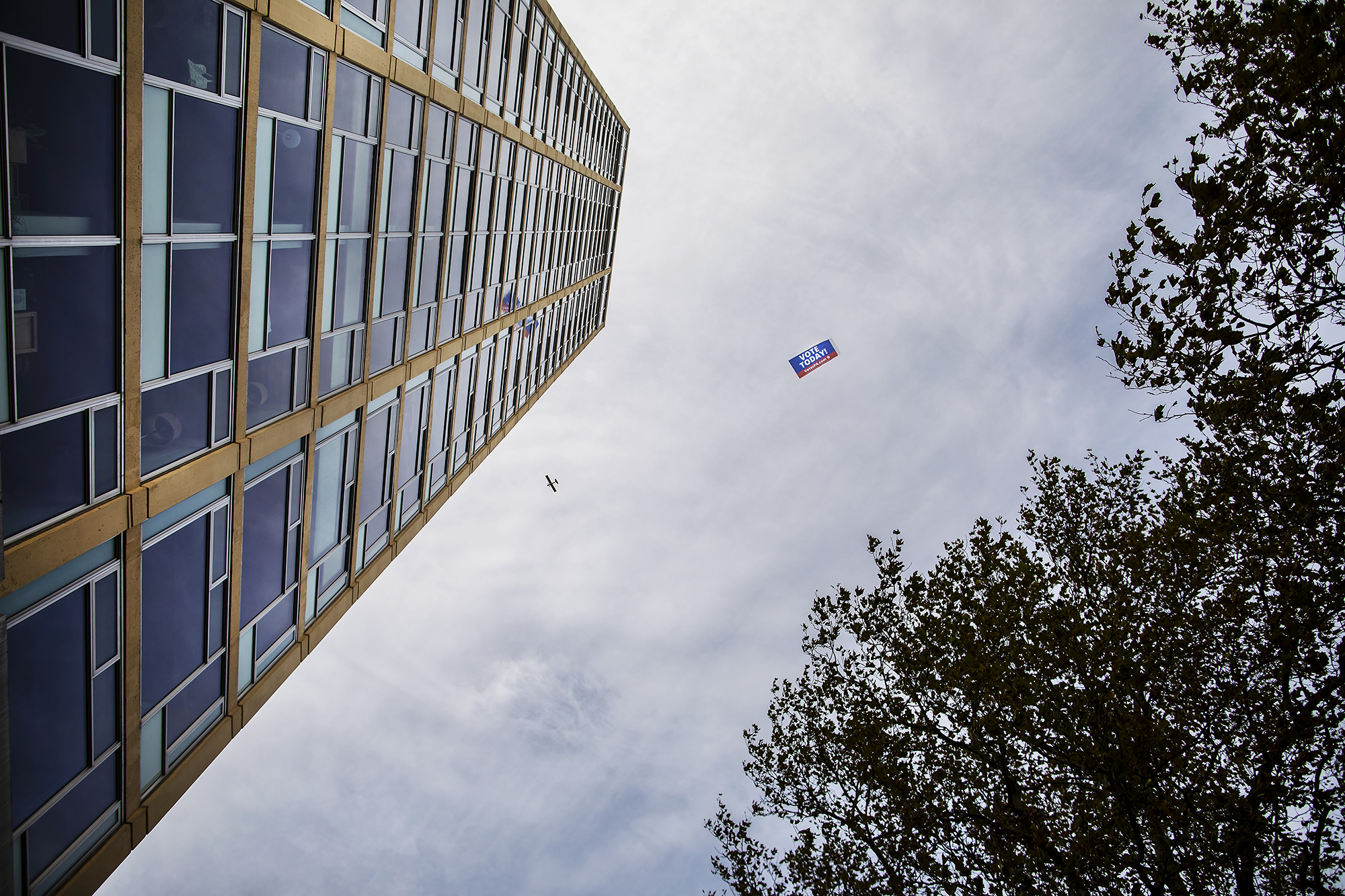 view looking at the sky with a plane pulling a sign that reads Vote Today