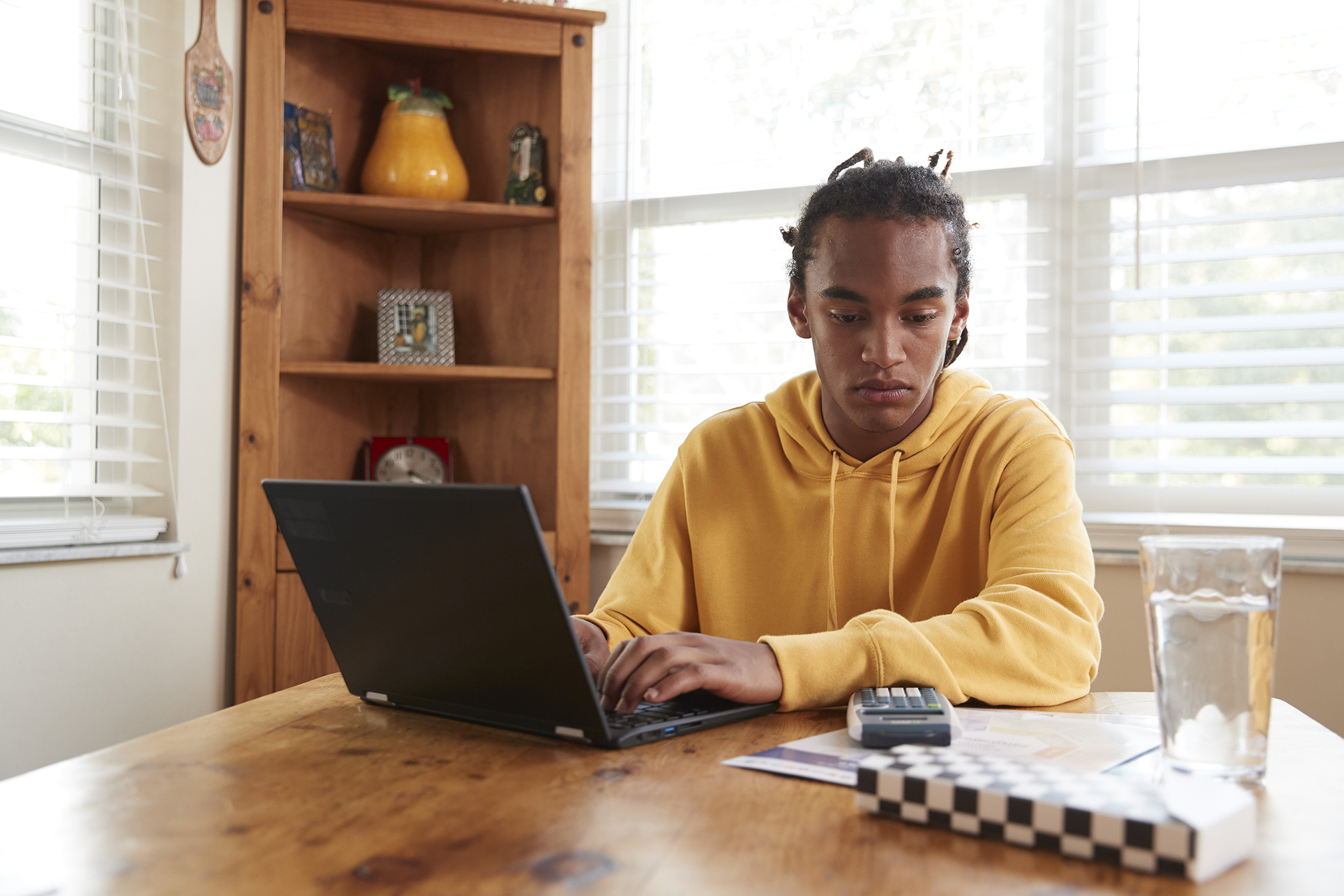 A high school student sits with a computer and calculator