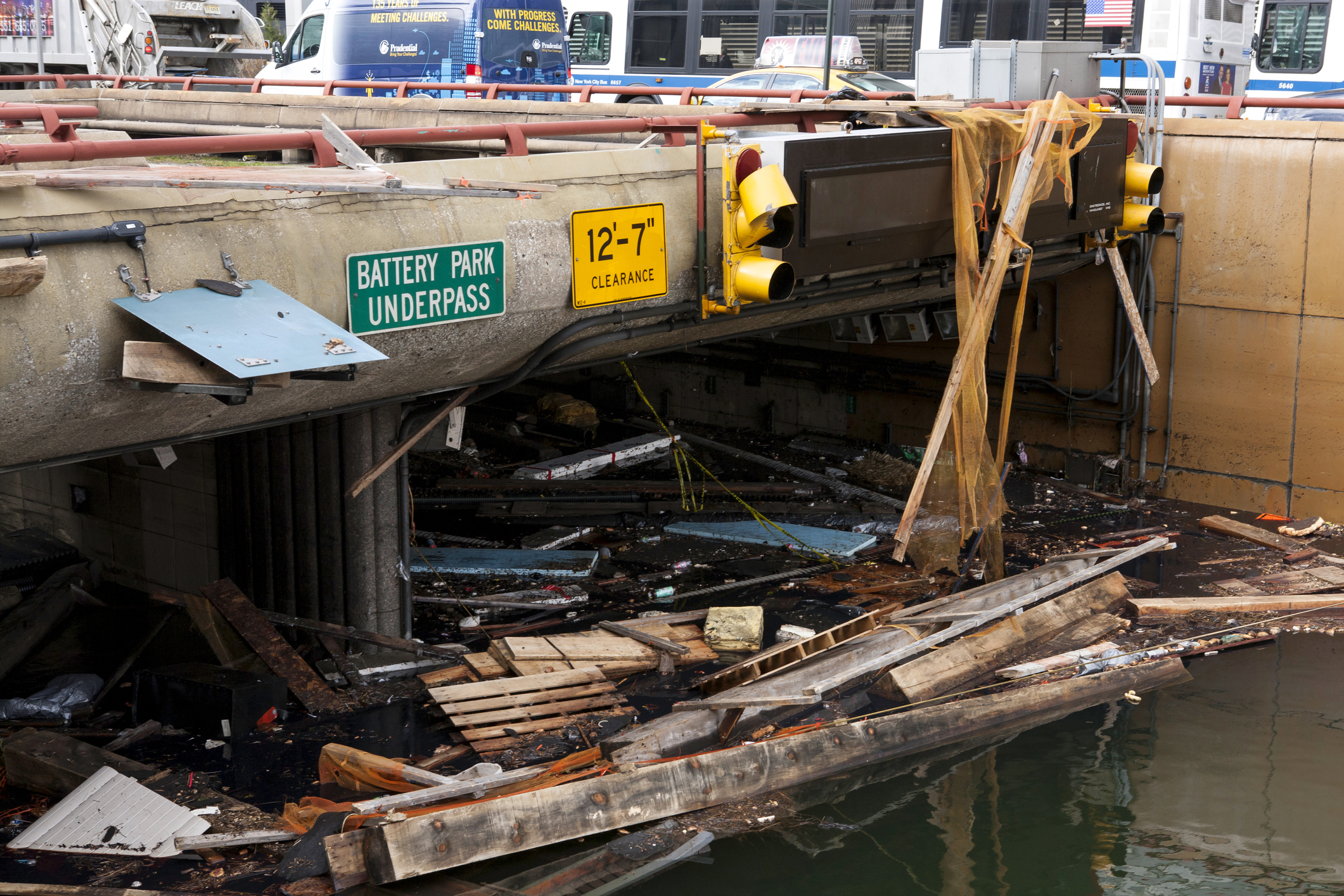 a flooded road covered in debris with a sign reading battery park underpass