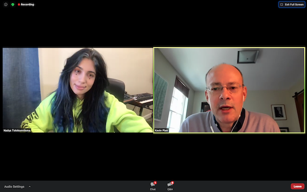 A computer screenshot of a Zoom call shows a woman with long black hair and neon green sweatshirt in a square on the left side of the screen, and a bald man with glasses and white earbuds on the right