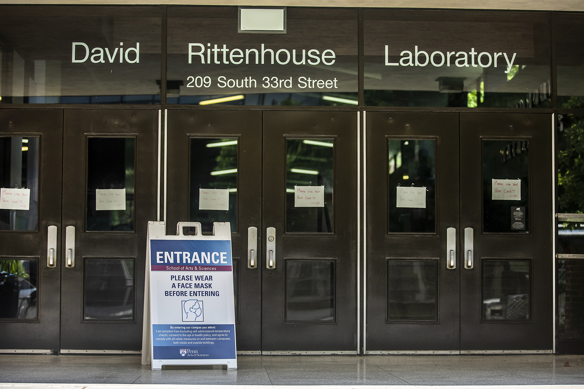 a sign in front of the david rittenhouse laboratory building that says entrance, please wear a face mask before entering