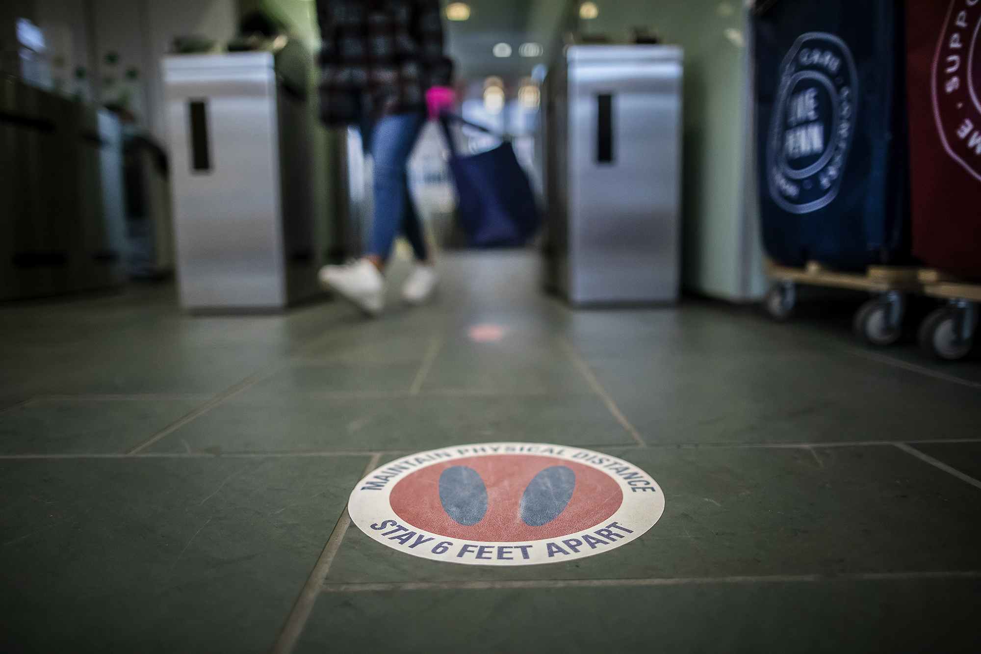 Sticker on floor with footprints in a circle that says stay six feet apart