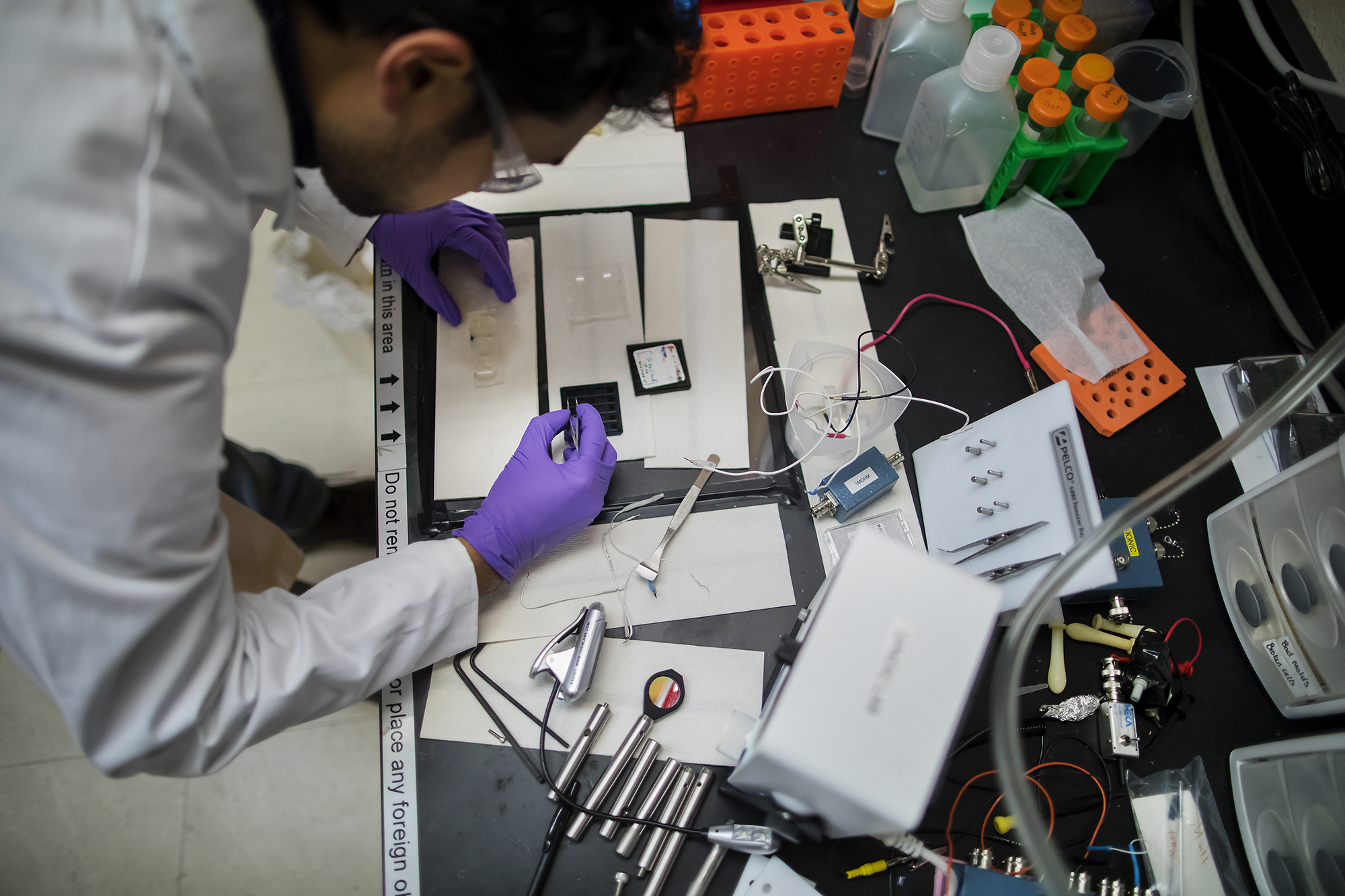 a person bent over with a pair of tweezers while working in a laboratory