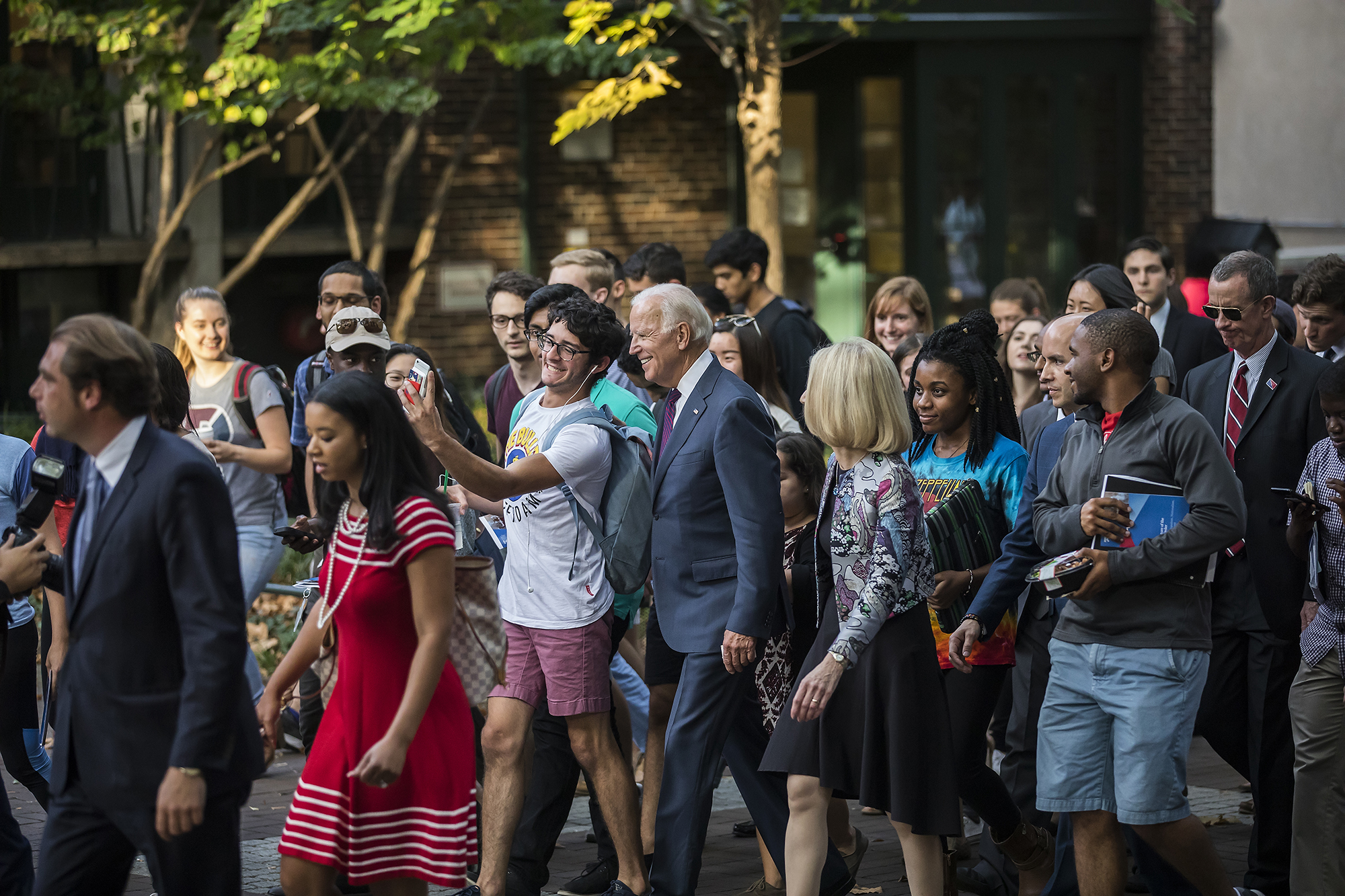 Biden walking on campus and taking a selfie with a student