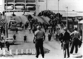 Historical image of police officers turning back a peaceful Civil Rights crowd of protesters at the foot of a bridge in Alabama.