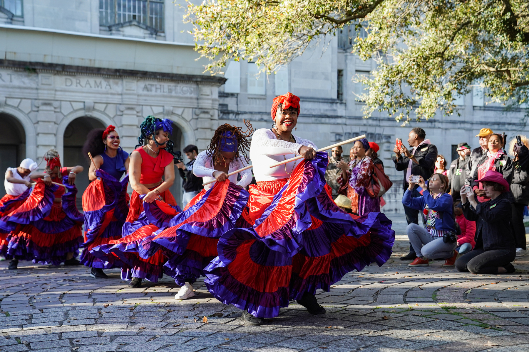 Street dancing in colorful costumes with standersby taking photos