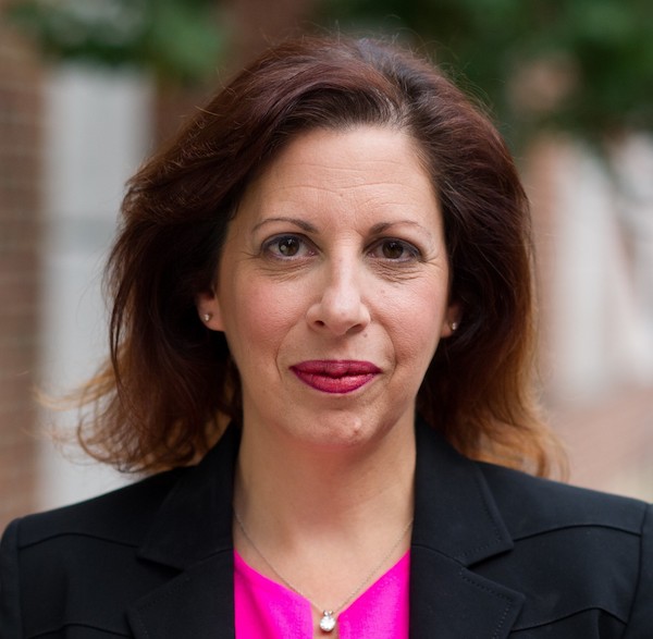 Woman wearing diamond earrings and black blazker looks into camera