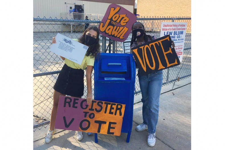 Two students standing with a mailbox puppet with signs reading "Vote That Jawn" and "Vote" and "Register to Vote" 