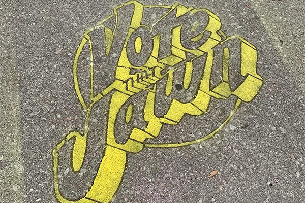 Vote That Jawn written in bright yellow chalk on the sidewalk