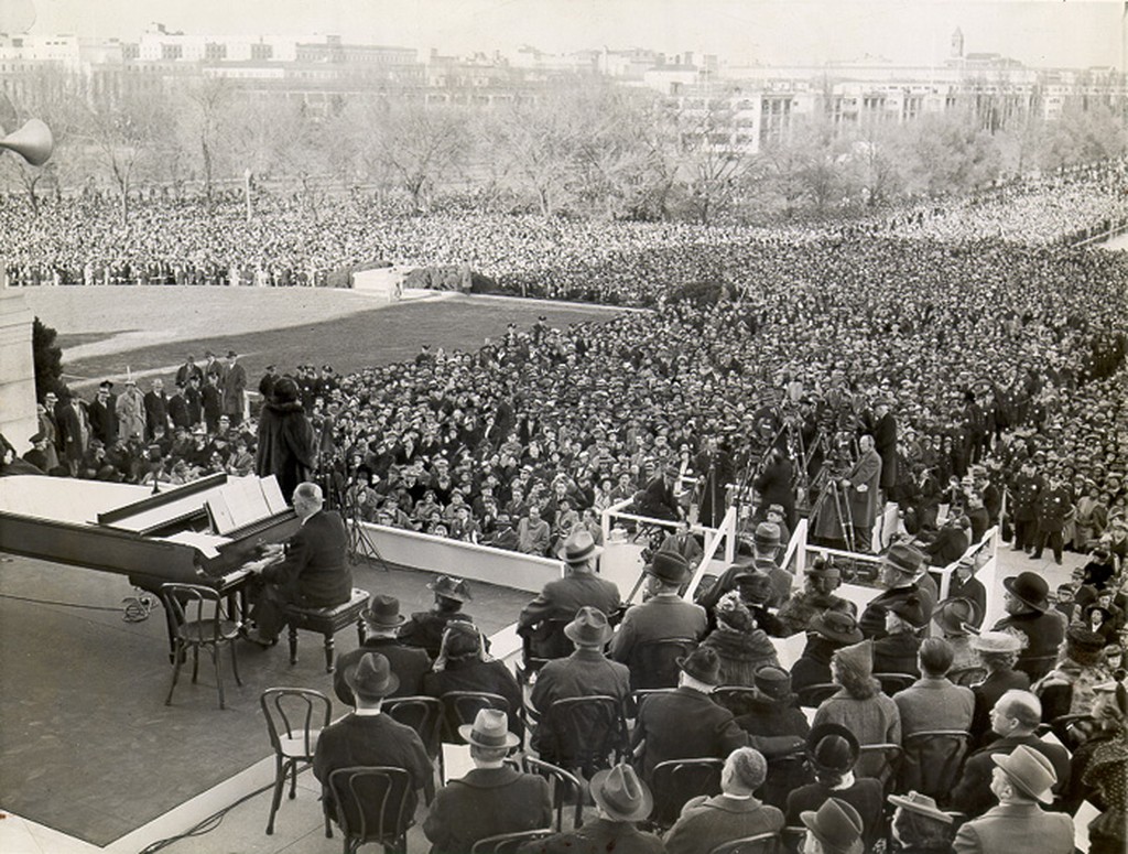 A woman accompanied by a pianist sings to a crowd of thousands on the Mall in Washington, DC