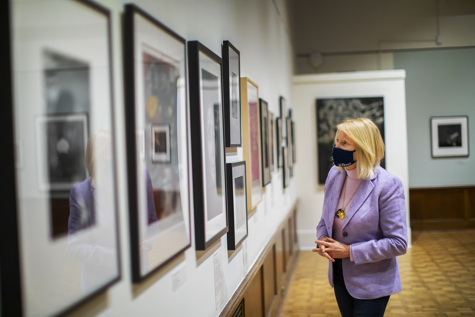 Curator standing in gallery looking at artworks on a wall