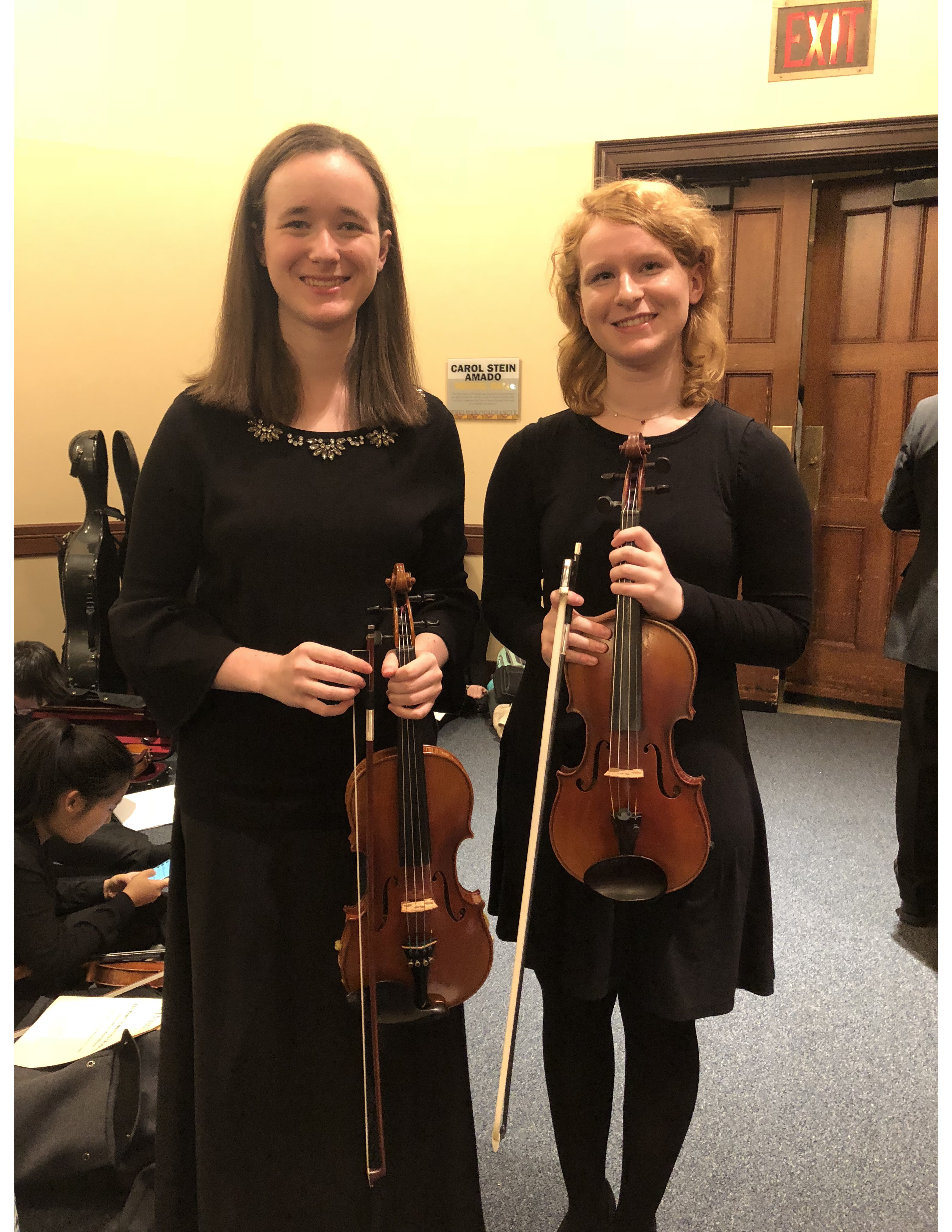 Two women in black hold violins