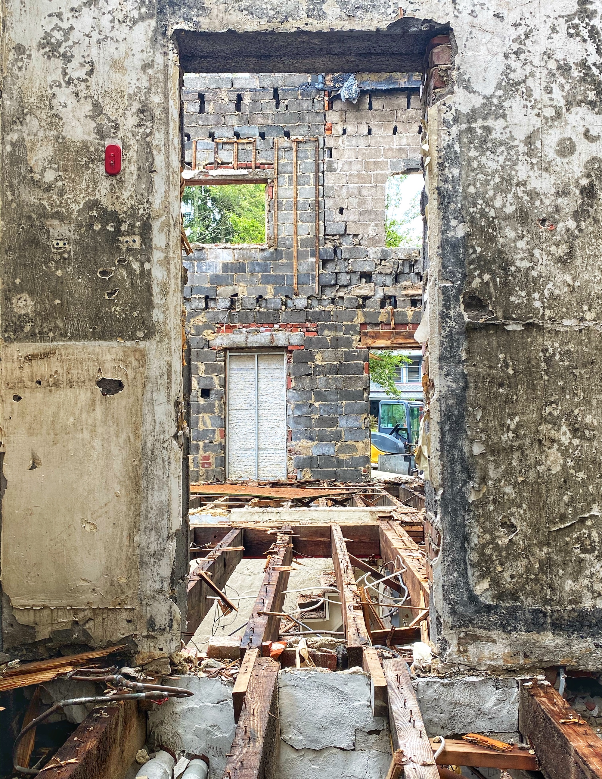 A building being torn down, seen through an open area that once held a door but is now just concrete.