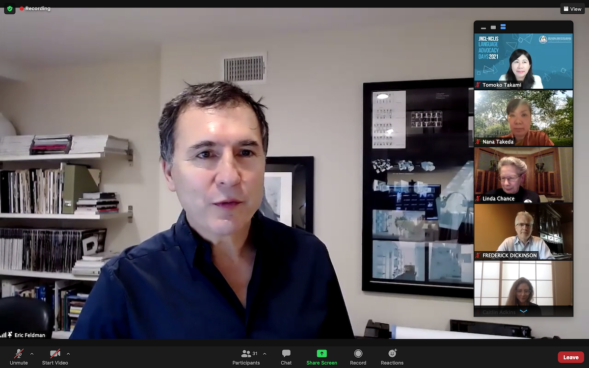Man speaks in a Zoom call with a vertical stack of five Zoom particpants on the right hand side of the image