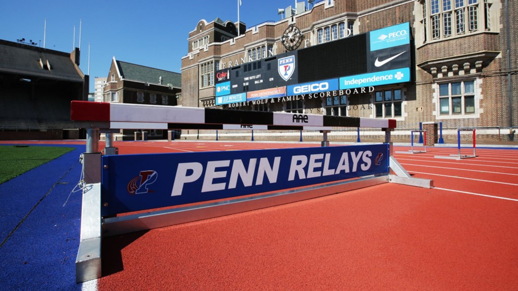 A hurdling bar displaying the words Penn Relays sits on the Franklin Field track.