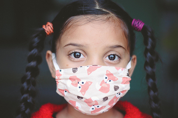 Young child’s face covered in a face mask covered in cartoon foxes.