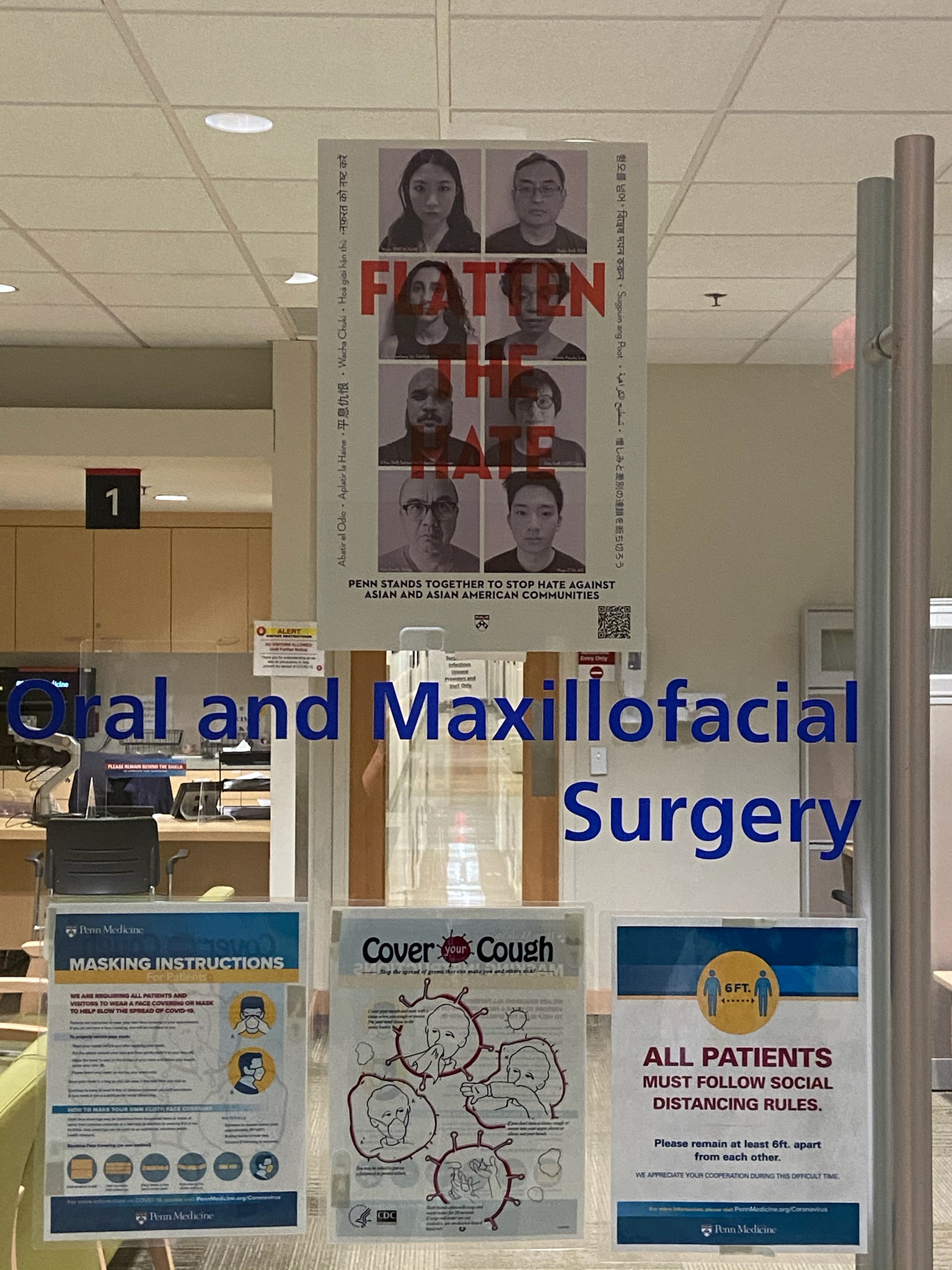 Glass window with "flatten the hate" poster and a sign that says "Oral and Maxillofacial Surgery"