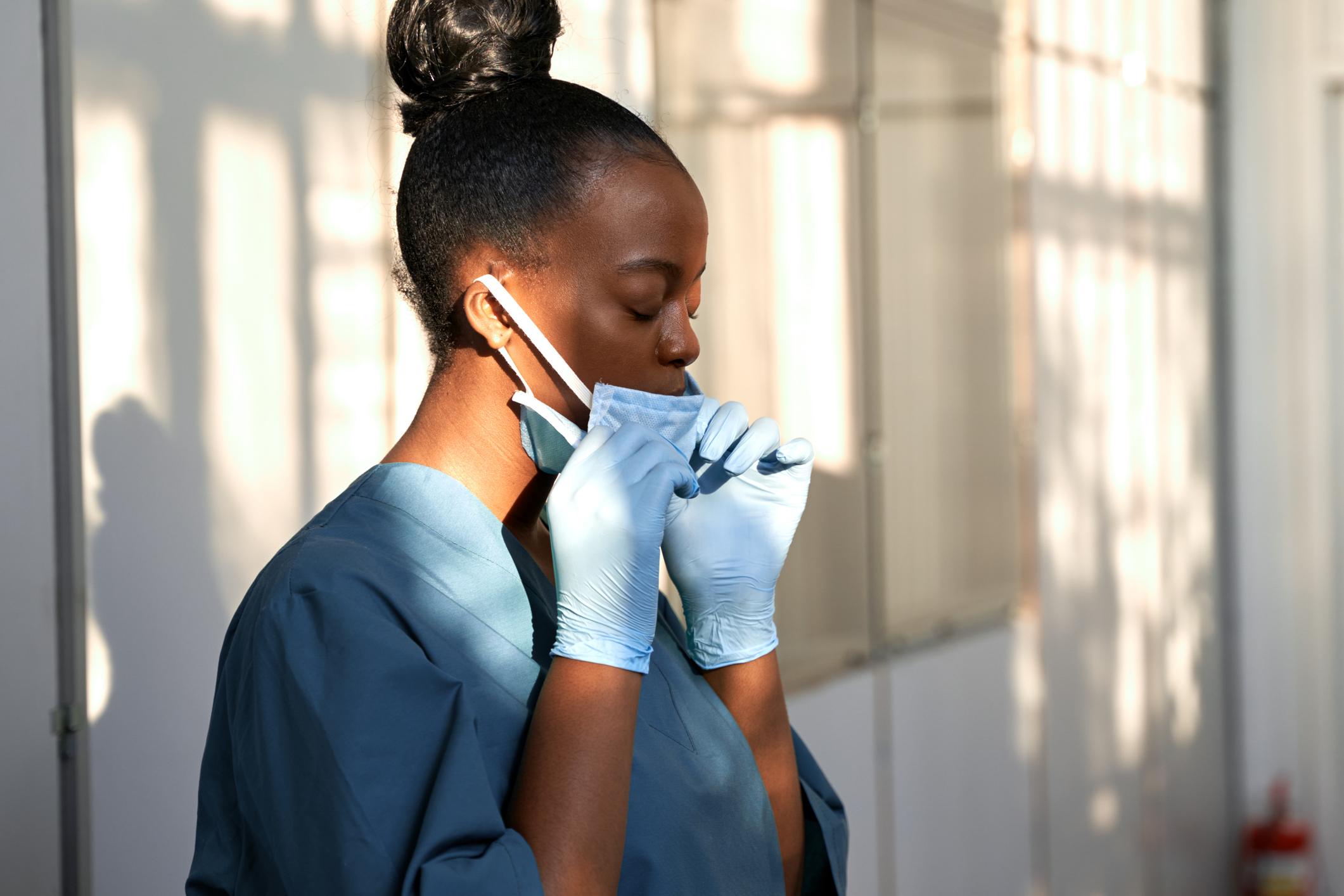 black healthcare worker pulling down mask